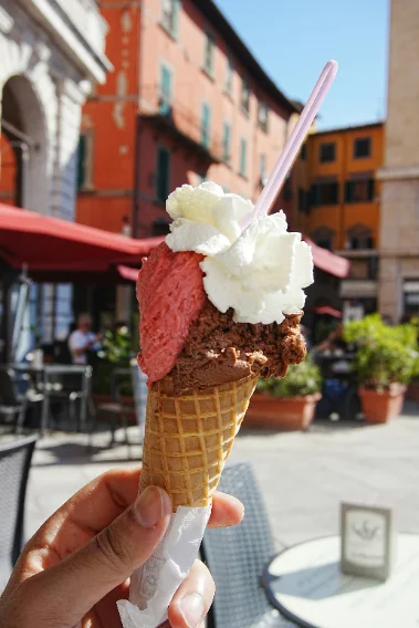 A hand holding a gelato cone in a Sicilian piazza