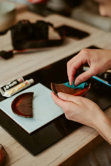 Hands repairing pottery with kintsugi in Japan